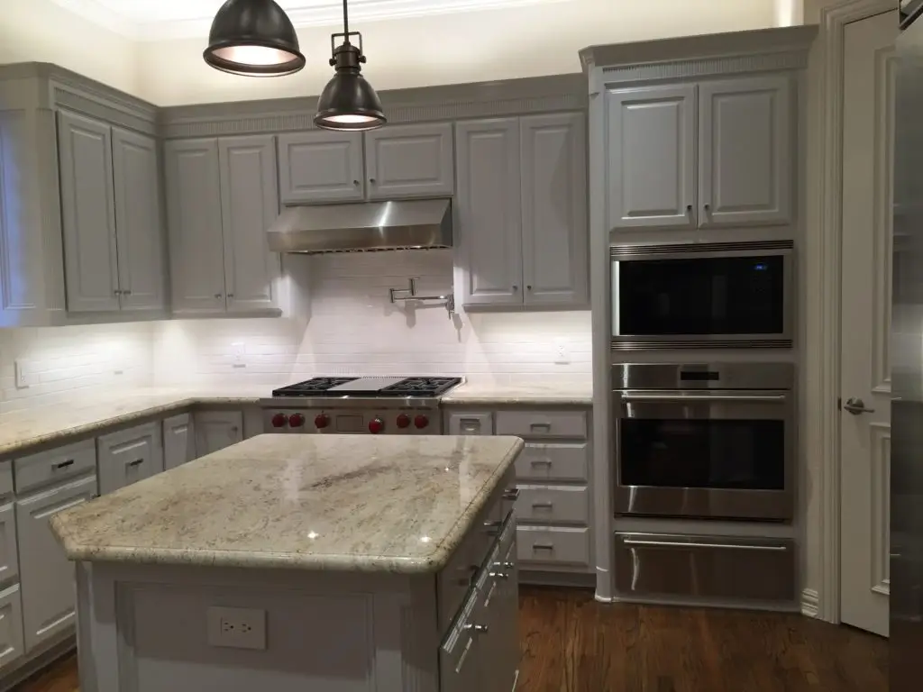 Elegant kitchen remodeling in Allen, TX showcasing a granite island, stainless steel appliances, and custom gray cabinetry with ambient lighting