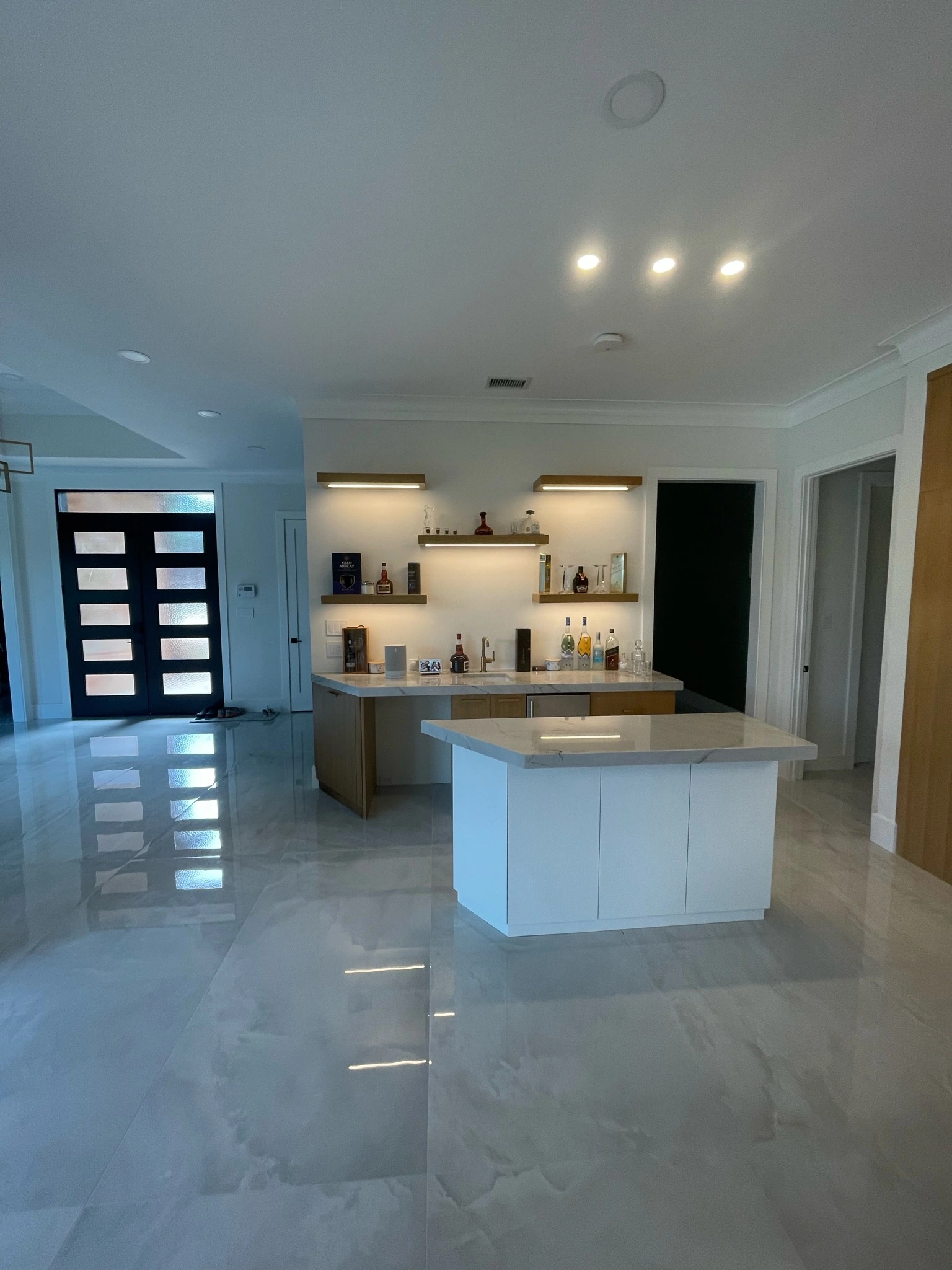 Open-concept living area featuring a custom home bar with floating shelves, marble floors, and modern lighting in a Home Renovation Dallas project