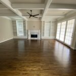 Spacious Plano living room with rich hardwood floors, natural light, and built-in shelving, showcasing the importance of proper hardwood floor maintenance in humid Texas seasons.