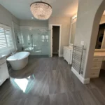 Elegant luxury bathroom remodel featuring freestanding soaking tub, crystal chandelier, and spacious glass shower in Plano.