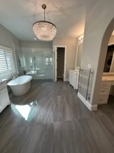 Elegant luxury bathroom remodel featuring freestanding soaking tub, crystal chandelier, and spacious glass shower in Plano.