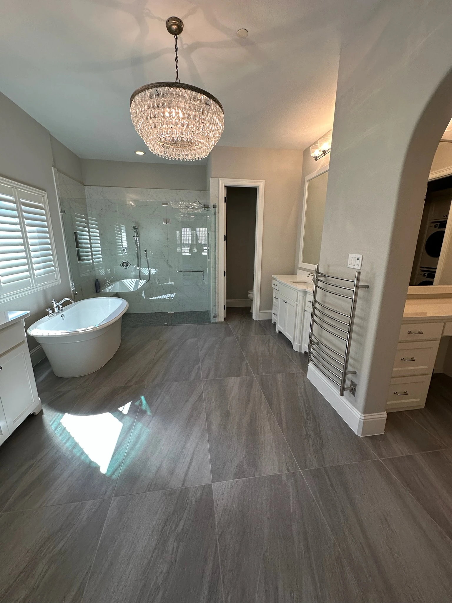 Elegant luxury bathroom remodel featuring freestanding soaking tub, crystal chandelier, and spacious glass shower in Plano.