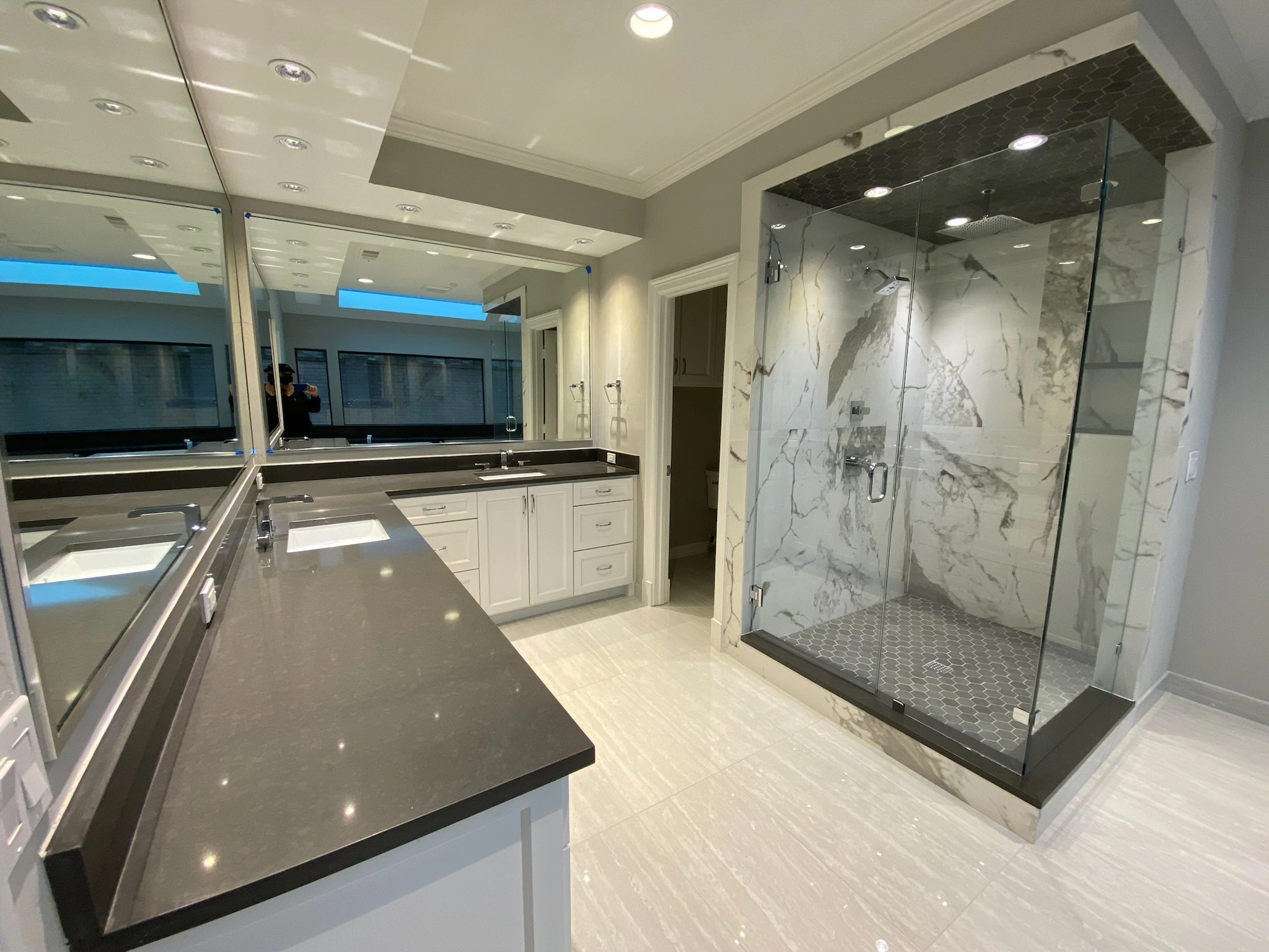 Sleek bathroom design with frameless glass walk-in shower, black quartz countertops, and double vanity.
