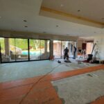 A spacious Plano home undergoing a full interior renovation with contractors installing large sliding doors and flooring, showcasing the work of leading Home Remodeling Contractors in Plano.