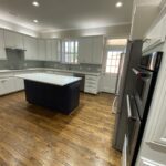 Luxury kitchen remodeling in Far North Dallas featuring custom white cabinetry, hardwood floors, and a modern center island - Home Platinum Services.