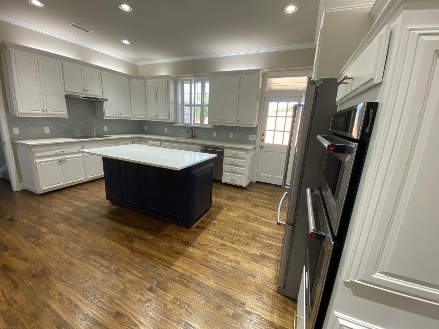 Luxury kitchen remodeling in Far North Dallas featuring custom white cabinetry, hardwood floors, and a modern center island - Home Platinum Services.
