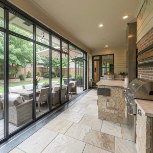 Homes built for entertaining design dallas: indoor-outdoor flow with retractable glass wall, outdoor dining, integrated grill station
